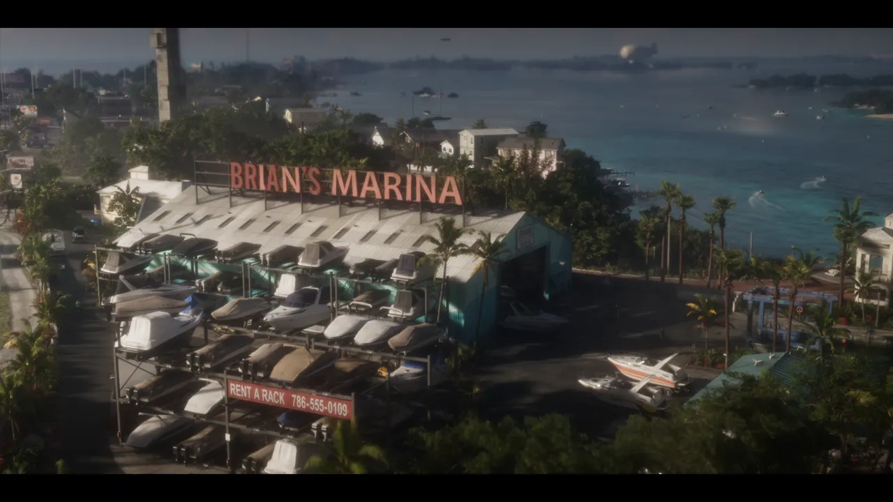 Aerial view of a marina: a "BRIAN'S MARINA" sign above a hangar, boats stacked on racks, a "RENT A RACK 786-555-0109" sign at the bottom of the racks, turquoise water in the background.