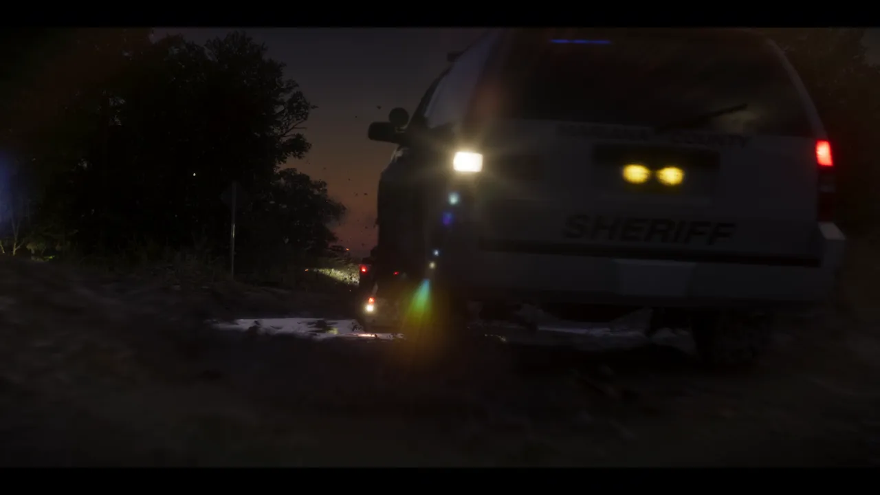 At night, the rear of a white SUV marked "SHERIFF" on wet ground at the edge of a wood, the sky still orange at the horizon.