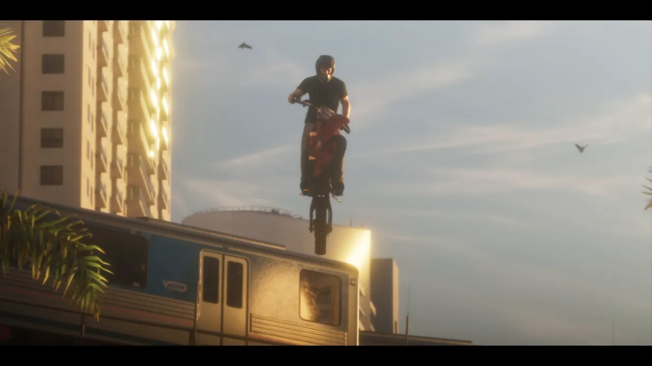 Un motard sur une moto tout-terrain rouge, en l'air au-dessus d'une rame de métro aérien, entre des immeubles.